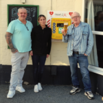 Dennis Frith shown on the right with a well-deserved pint in front of the defibrillator bought with money raised through a campaign with The Rumbold Arms in Great Yarmouth