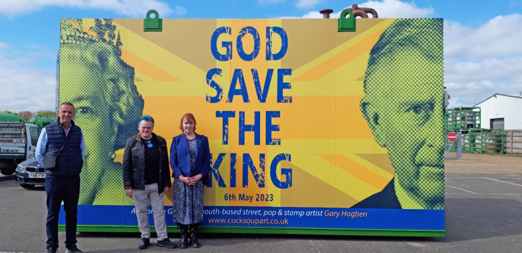 A huge industrial storage tank with a graphic of Queen Elizabeth II and King Charles with words God Save The King