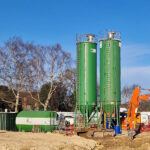 Two ATI Tank Hire 45m³ vertical gravity silos and a horizontal storage tank on a construction site