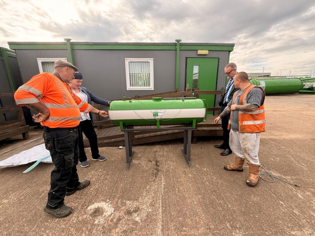 4 people standing around miniature tank